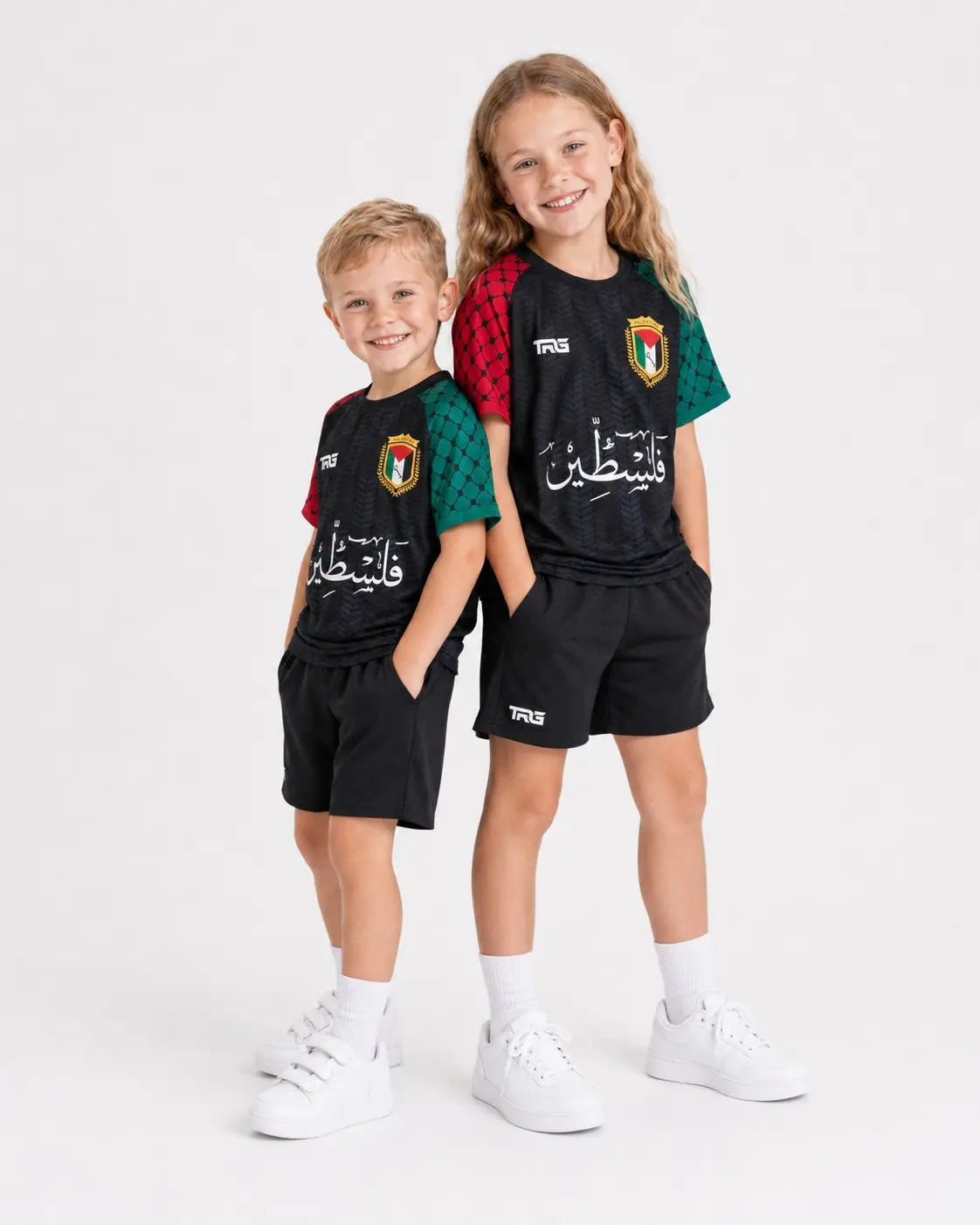 Two children wearing black TRG Kids Palestine football jerseys with red and green sleeves on a white studio background.