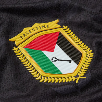 Close-up of the Palestine badge on the black TRG Kids football jersey.