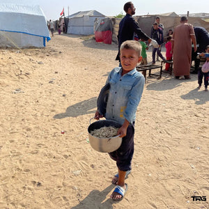 Young boy carrying food pot at displacement camp in Gaza by The Real Guys