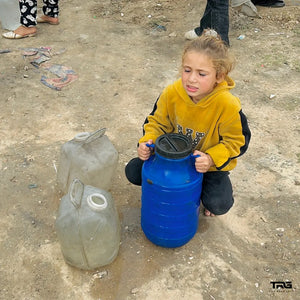 Young girl collecting water containers at displacement camp in Gaza by The Real Guys