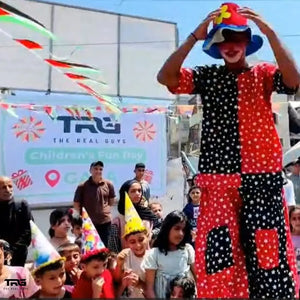Clown in a colorful outfit performing at a Children's Fun Day event with TRG branding.