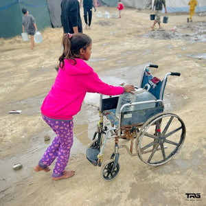 Girl using wheelchair to carry water container at displacement camp in Gaza by The Real Guys