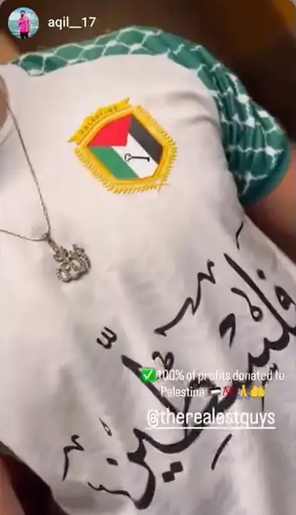 White shirt with Palestinian flag emblem and Arabic text, worn by a person.