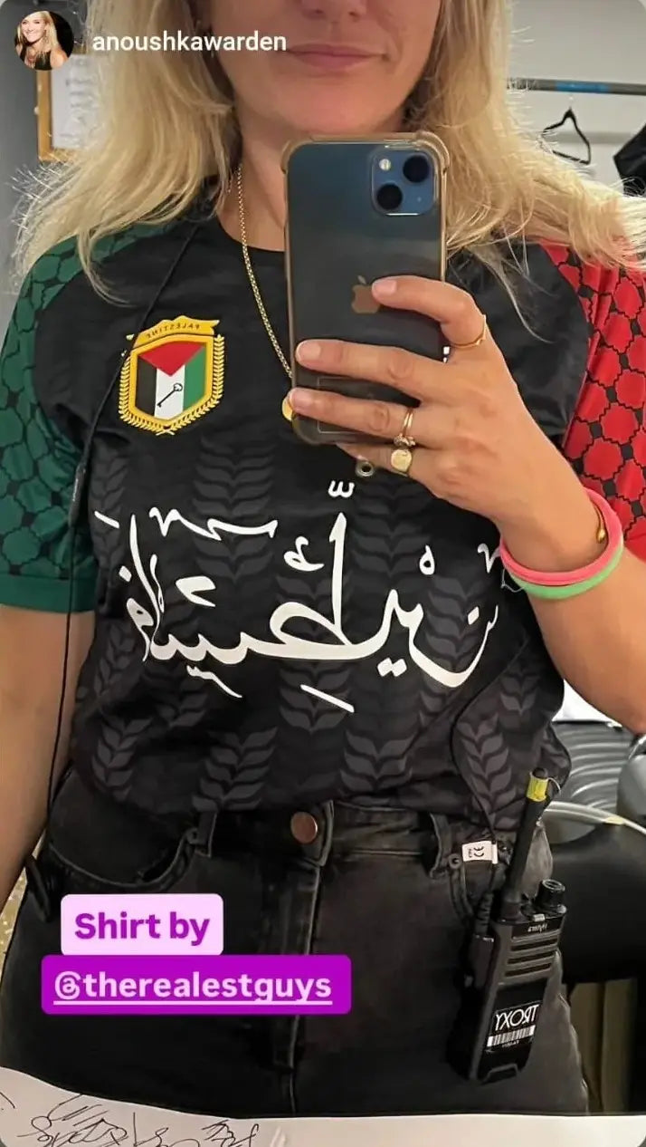 Woman wearing Palestine football jersey black short sleeve mirror selfie with Arabic calligraphy